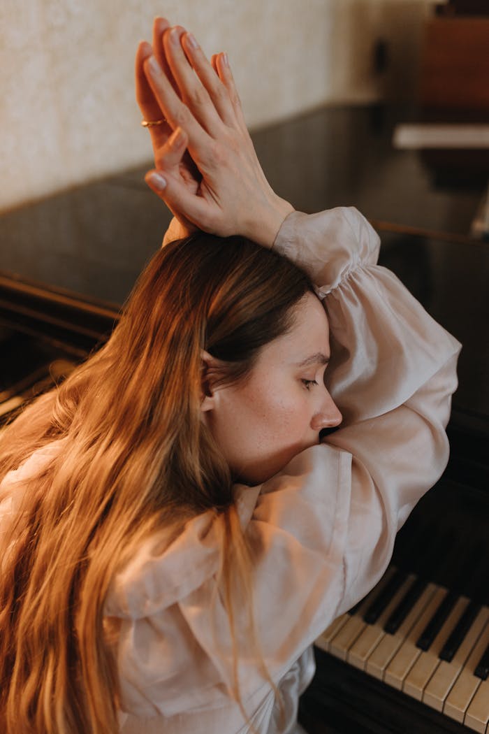 A woman is sitting at a piano and stretching her arms